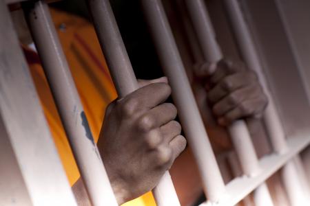 An incarcerated man grips prison bars