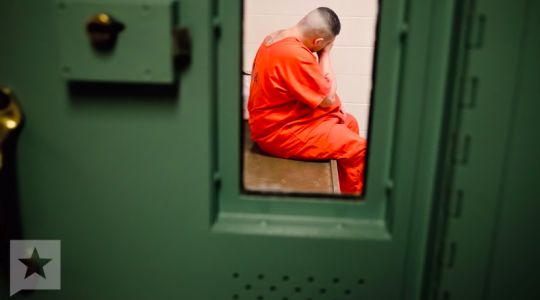 Incarcerated man in isolation, seen through a narrow window in the door