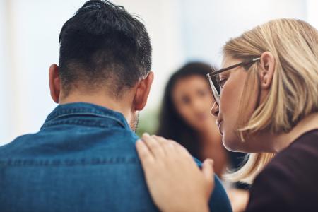 A therapist with hand on a young man's shoulder