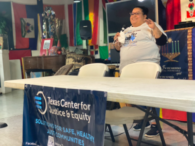 Maggie speaking at a From Prison to Power event behind a table with an SLC banner