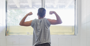 Incarcerated teen in strong pose in front of window