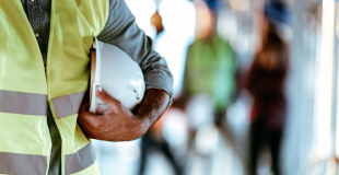 Worker in safety vest holding helmet