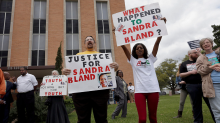 Protestors holding signs that read "the whole truth and nothing but the truth" "what happened to Sandra Bland?""justice for Sandra Bland" 